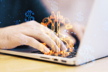 Close up of businessman hands using laptop keyboard with abstract glowing dollar sign hologram on blurry background. Online banking, technology, data and finance concept. Double exposure.
