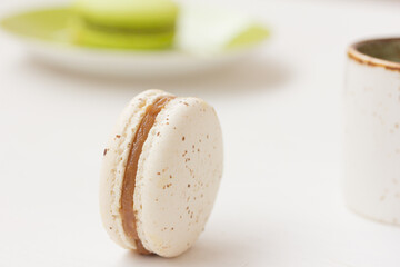Macaron, cup of coffee on white background. Salted caramel macaroon, Pistachio nut macaroon. Close up