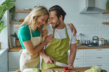 Happy young couple cooking together and bonding at the domestic kitchen