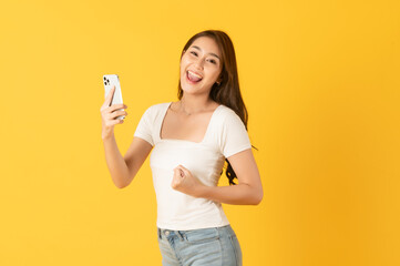 Surprise happy asian beautiful woman isolate on yellow background using smartphone