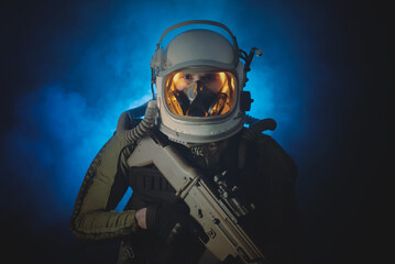 Spaceman or star trooper in the helmet and with rifle in the blue smoke. Science fiction concept. - obrazy, fototapety, plakaty