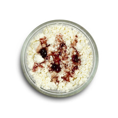 Cottage cheese with red jam in a glass plate. Close up. Isolated on a white background