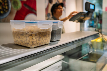 An unrecognizable young female shop assistant serving a male customer in a zero-waste store. Top view.