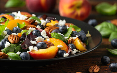 Peach, blueberry salad with vegetables, feta cheese and pecan nuts. Healthy summer food