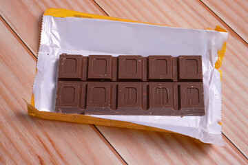 TABLETA DE CHOCOLATE NEGRO SOBRE MESA DE MADERA.