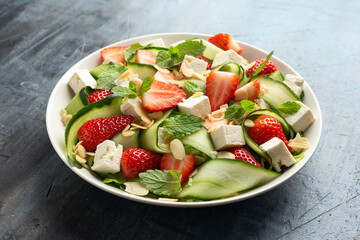 Summer Strawberry, cucumber salad with lettuce, feta cheese and almonds. Healthy Food.