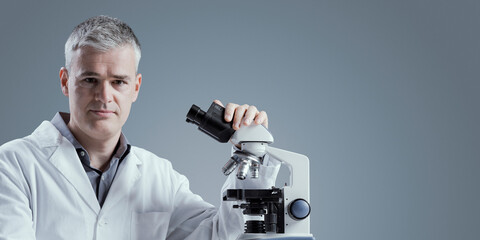 Medical scientist posing with a microscope