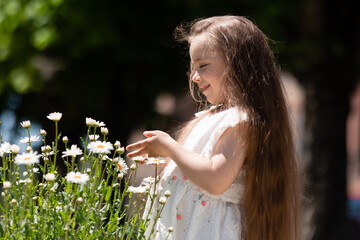 Beautiful Little girl in white dress with flowers in park summertime