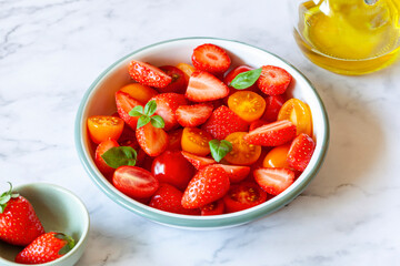 Tomato cherry and strawberry salad on the marble background