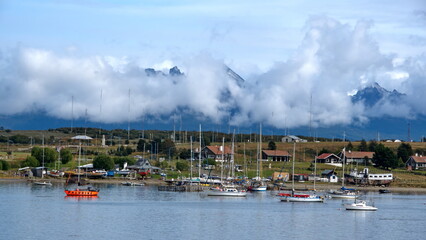 Fototapeta na wymiar Sailboats moored in the harbor in Ushuaia, Argentina, beneath cloud shrouded mountains