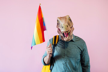 Man with lizard mask on pink background with colorful pride flag.