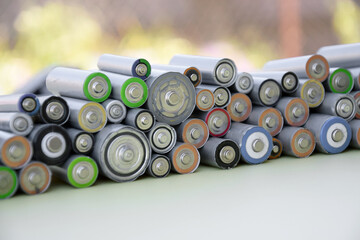 Used AA batteries and proper disposal of environmentally and soil-toxic batteries on a green...