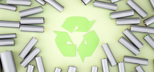 Used AA batteries and proper disposal of environmentally and soil toxic batteries on a green...