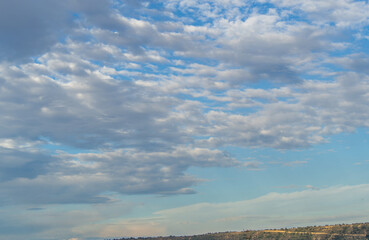 Ornamental clouds. A dramatic sky. Epic cloudy storm landscape. Soft sunlight. Panoramic image, texture, background, graphic resources, design, copy space. Meteorology, sky, hope, peace concept