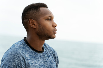 Handsome fitness multiracial man at the beach on a summer day standing in relaxed pos