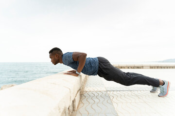 Fototapeta na wymiar Mixed race athletic man with muscular body doing push ups exercise