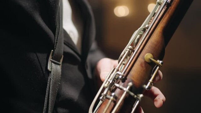 old bassoon in hands of musician, closeup view, symphonic or brass orchestra, talented bassoonist
