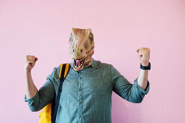 Man with lizard mask on pink background showing his muscles.
