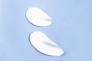 Smears of body cream, lotion, tanner on a blue background top view.