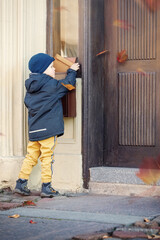 Little boy with an envelope at post office. Child sending letter. Kid throwing card into a mail box. Postal service in Europe. Delivery and shipment at outdoor mailbox.