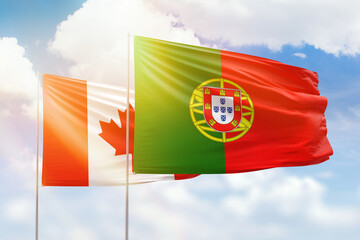 Sunny blue sky and flags of portugal and canada