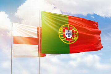 Sunny blue sky and flags of portugal and england