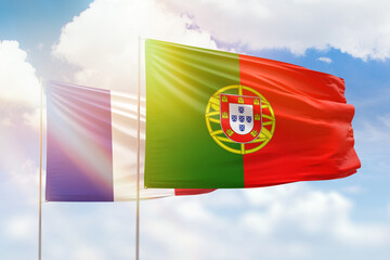 Sunny blue sky and flags of portugal and france