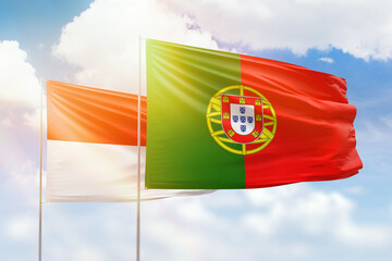 Sunny blue sky and flags of portugal and indonesia