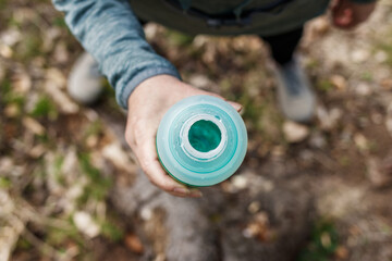 Woman drinking water from bottle. Resting during hiking in forest. Top view. Fitness and sport activity