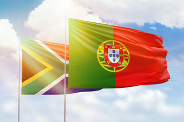 Sunny blue sky and flags of portugal and south africa