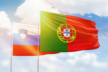 Sunny blue sky and flags of portugal and slovenia