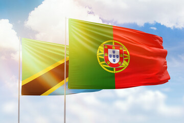 Obraz premium Sunny blue sky and flags of portugal and tanzania