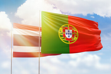 Sunny blue sky and flags of portugal and thailand