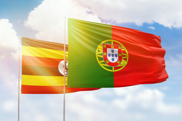 Sunny blue sky and flags of portugal and uganda