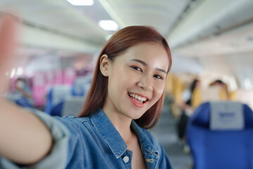 Fototapeta premium Travel, tourism business, portrait of a woman using her phone selfie on an airplane to post a profile picture of herself