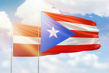 Sunny blue sky and flags of puerto rico and latvia