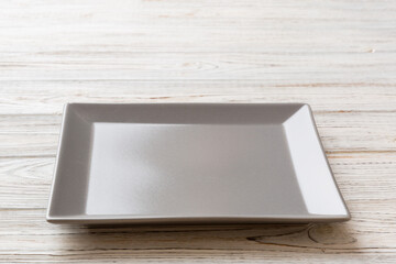Fototapeta premium Perspective view of empty square plate on wooden background. Empty space for your design