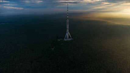 Aerial panoramic sunrise morning view on telecommunication tower antenna in forest and scenic...