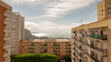 The Mediterranean Sea coast at Alicante viewed from between two apartment blocks and over an empty children’s play area.