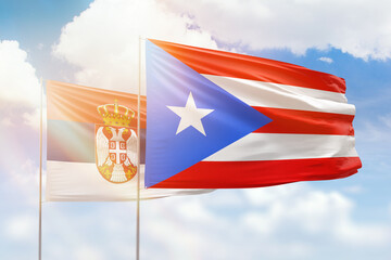 Sunny blue sky and flags of puerto rico and serbia