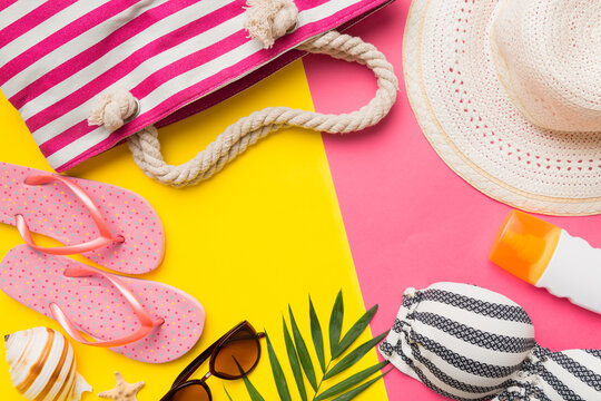 Beach accessories straw hat and seashell on colored table. Summer concept background