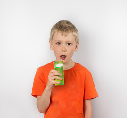 a boy in an orange T-shirt drinks apple juice from a box.