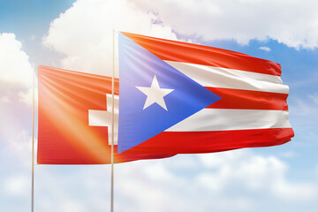 Sunny blue sky and flags of puerto rico and switzerland