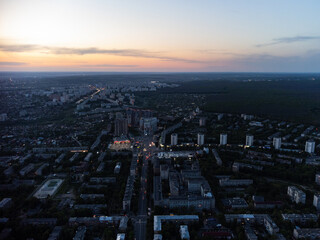 Fototapeta na wymiar Aerial sunset evening view on residential Kharkiv city Pavlove Pole district streets with lights. Gray multistory buildings with scenic vivid sunset cloudy sky