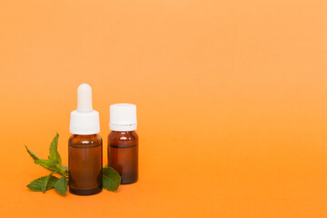 Natural Mint Essential Oil in a Glass Bottle. organic cosmetics with herbal extracts of mint on colored background