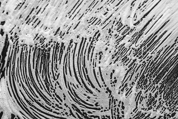 white foam streaks on smooth black surface, abstract background