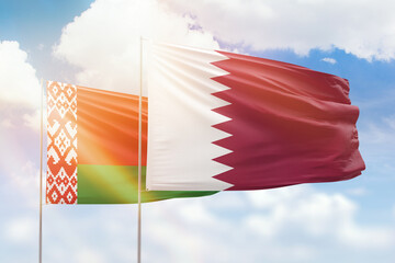 Sunny blue sky and flags of qatar and belarus