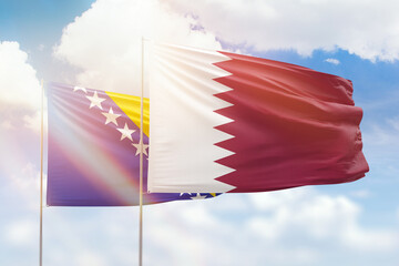 Sunny blue sky and flags of qatar and bosnia