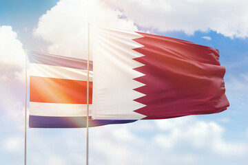 Sunny blue sky and flags of qatar and costa rica