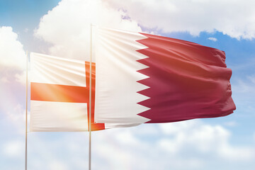 Sunny blue sky and flags of qatar and england
